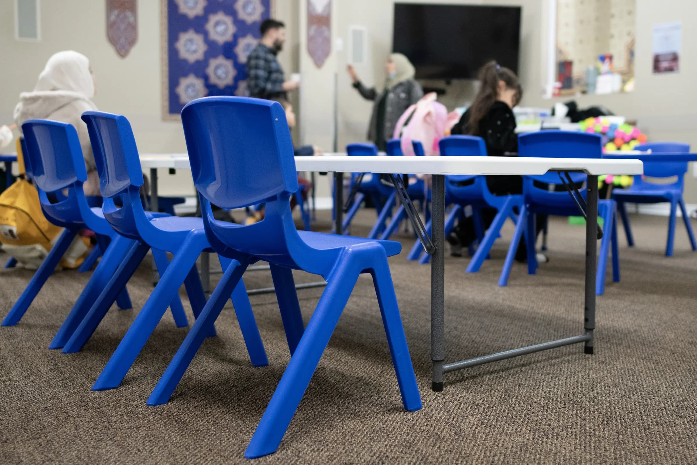 A classroom at Al-Ridha Academy with child-sized blue chairs and tables